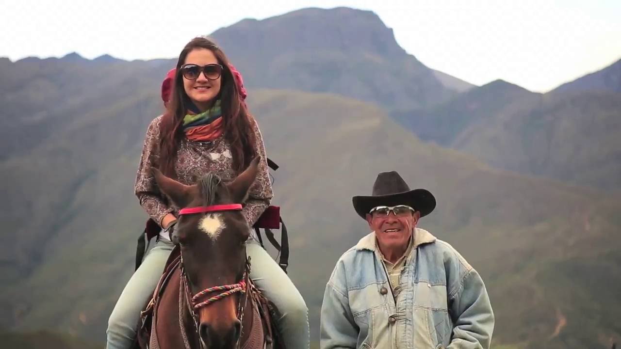 una mujer montando un caballo y un hombre con un sombrero a su lado