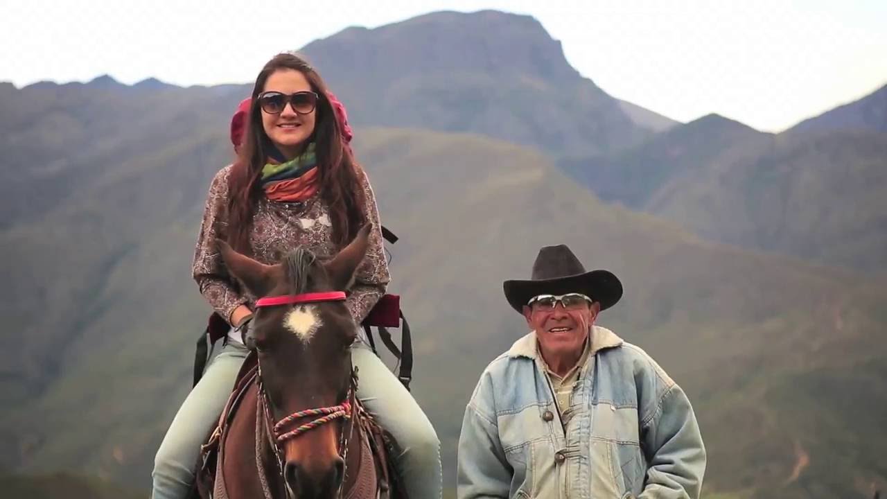 a woman riding a horse and a man with a hat next to her