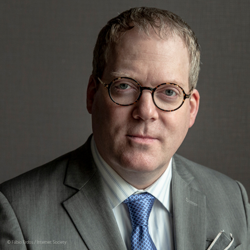 a man with glasses wearing a suit posing for a headshot