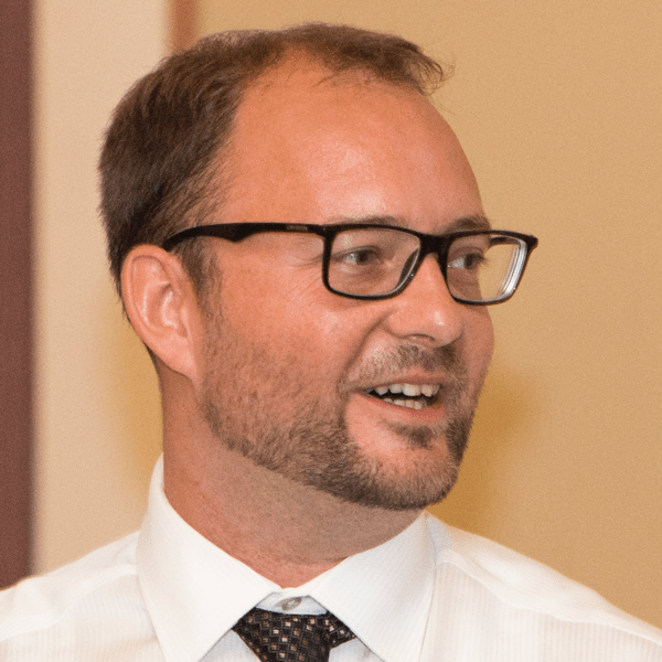 A headshot of a man with glasses