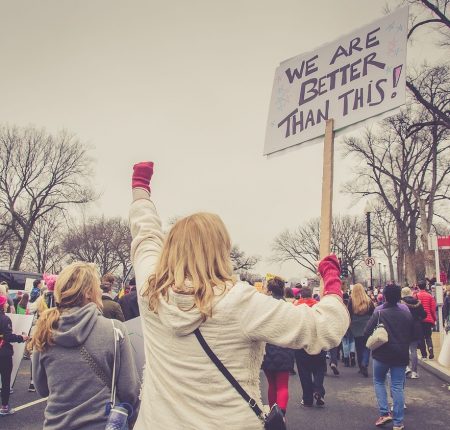 a group of protesters with a woman holding up a sign