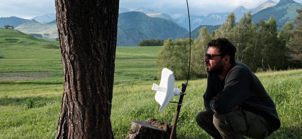 a man in a field checking if antenna is aligned