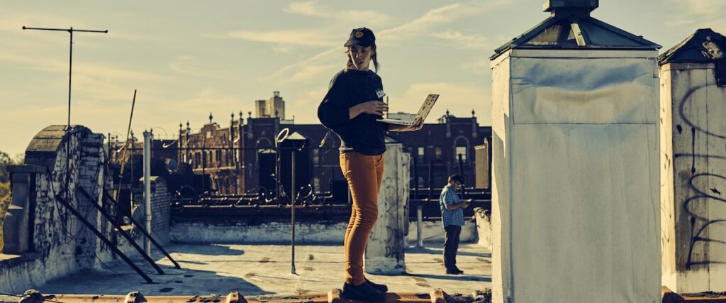 a girl holding laptop on a roof