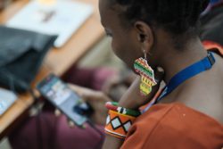 A woman with Africa earing looking at a phone