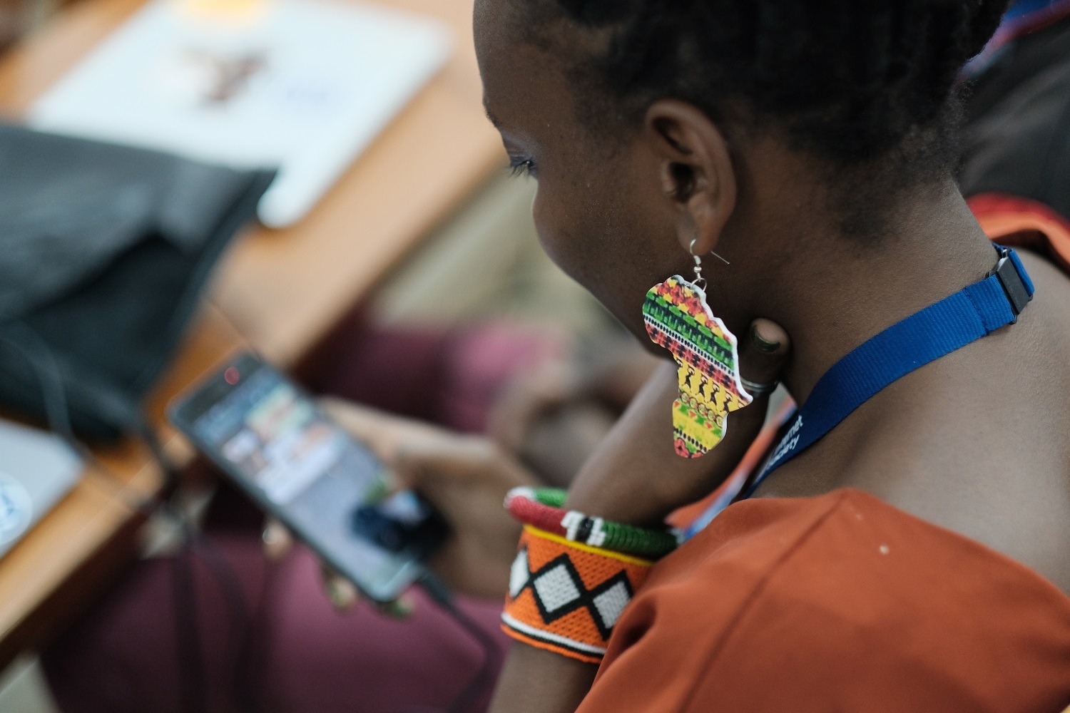 une femme avec des boucles d'oreilles colorées regardant le téléphone