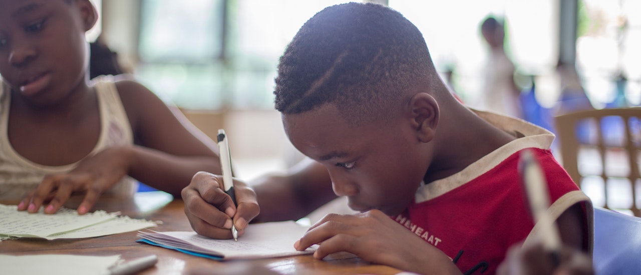 Dos niños sentados en el escritorio y escribiendo en cuadernos