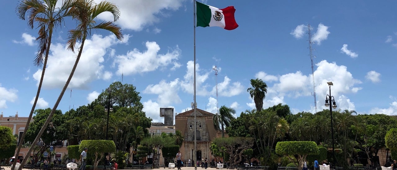 un parc devant le bâtiment avec le drapeau mexicain au centre