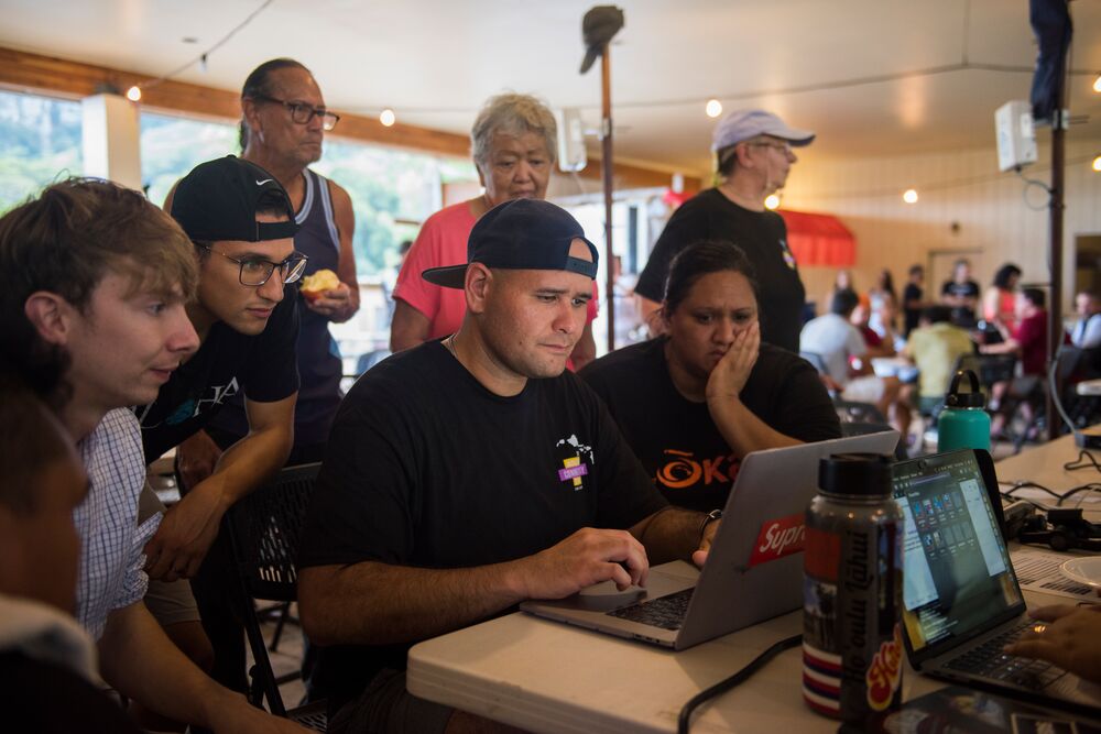 a group of people around the computer searching for something online