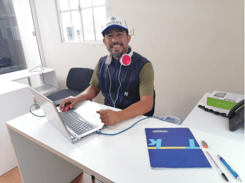 a man sitting behind the laptop with headphones around his neck