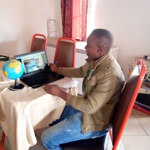 Un homme assis à la table devant l'ordinateur portable avec un petit globe à côté