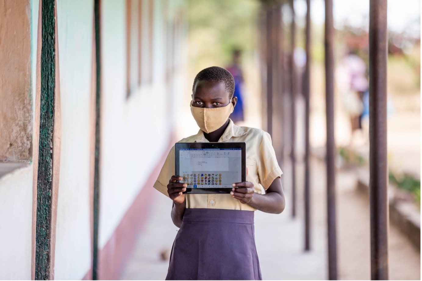 Child wearing mask and holding a tablet