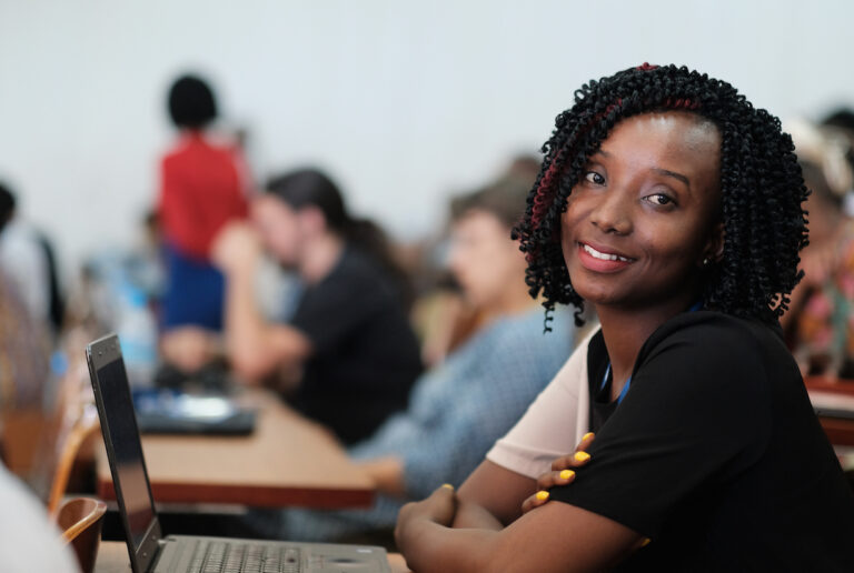 a woman smiling at camera, sitting at a desk