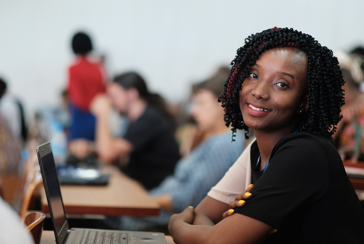 An African woman looking at camera while sitting in front of her laptop at an event