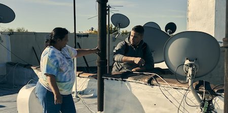 un hombre y una mujer en el techo de un edificio entre antenas