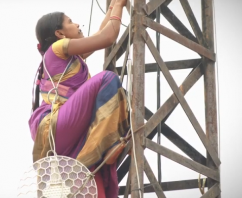 A woman climbing on antenna pole