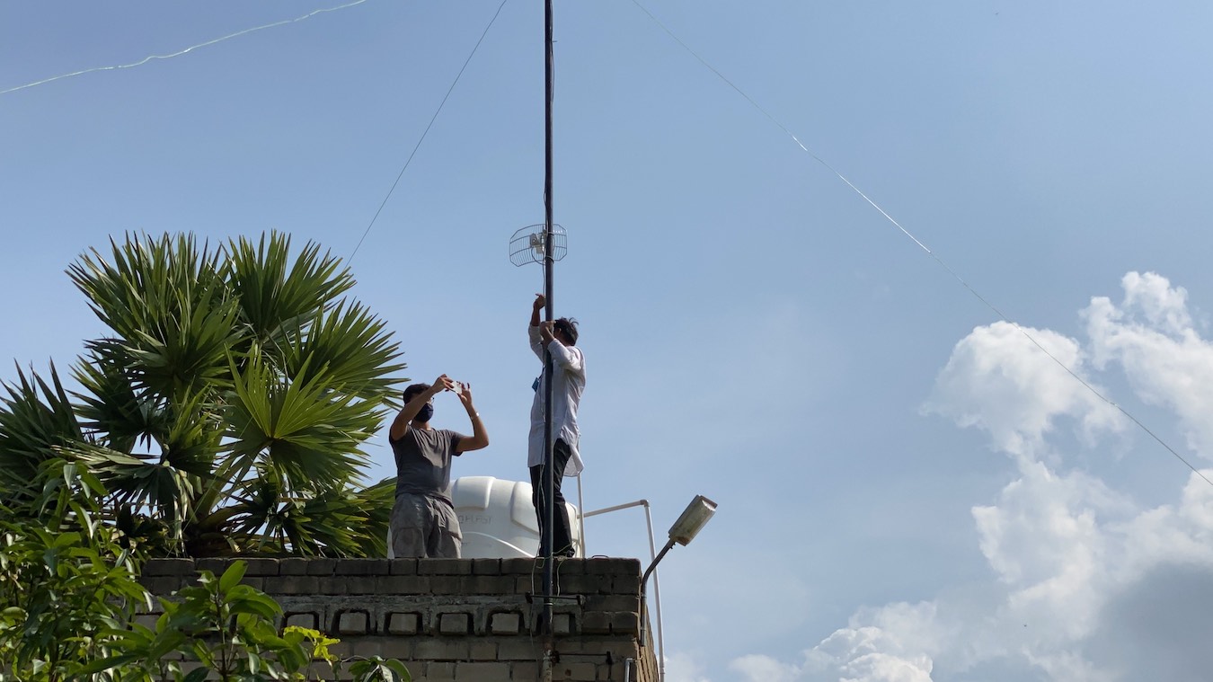 Two men installing the antenna on the roof
