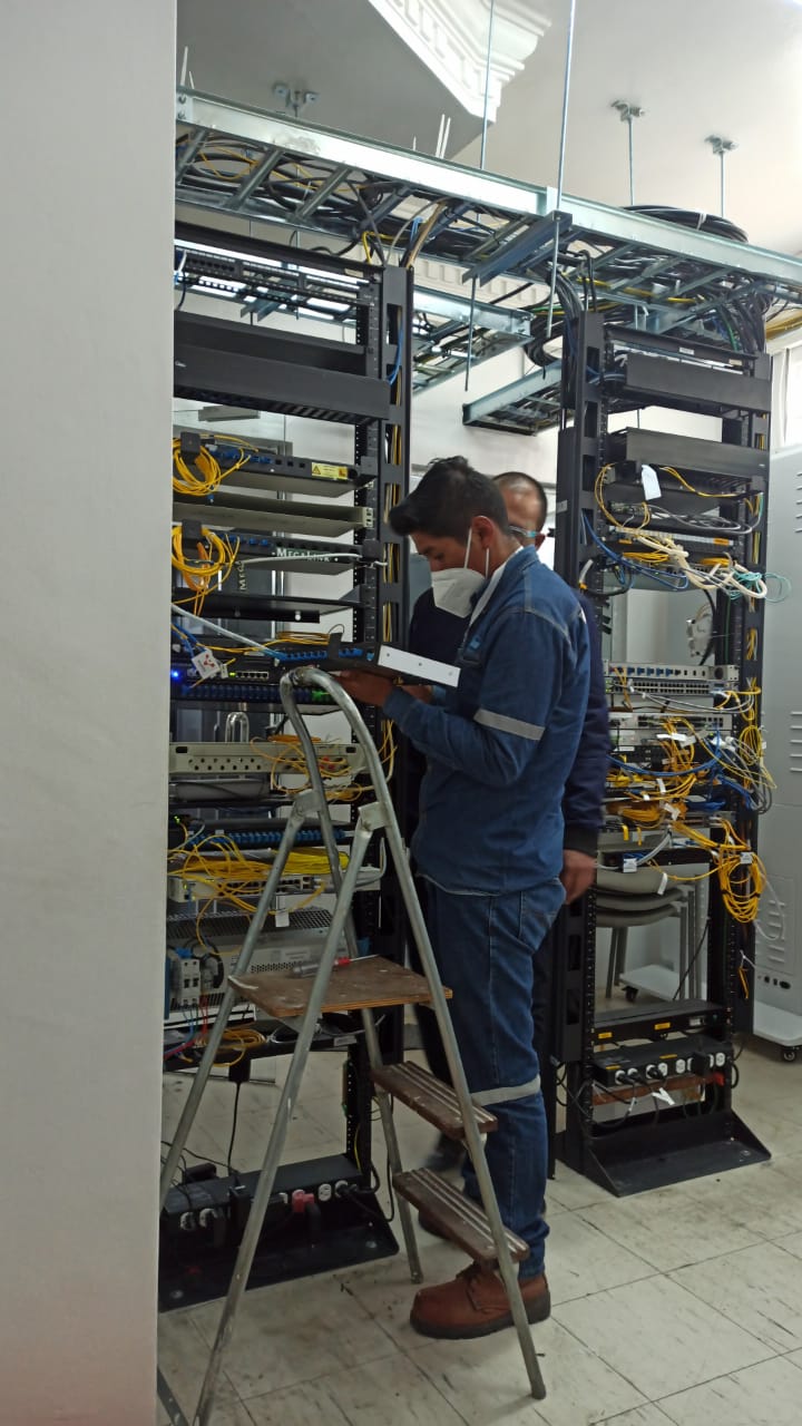 Two men checking routing equipment with ladder in front of them