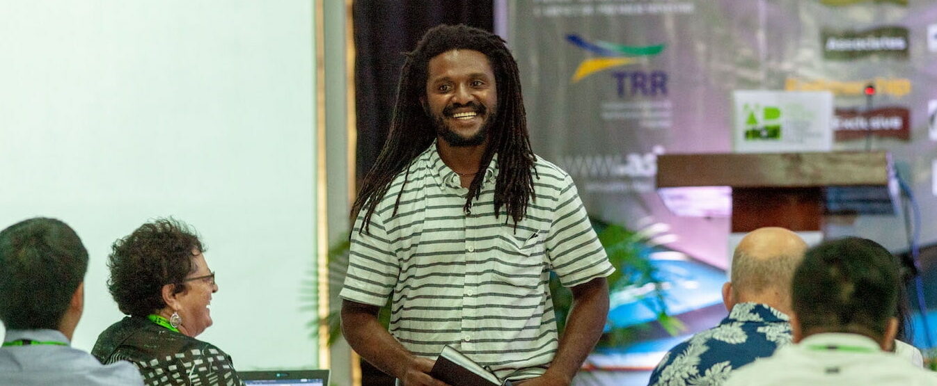 Man with long hair smiling walking between the lines at an event