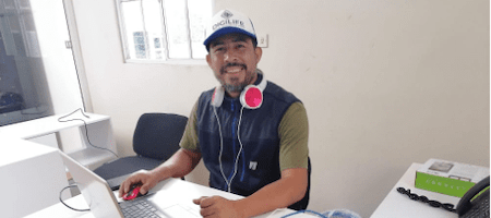 Un homme assis à un bureau devant un ordinateur souriant