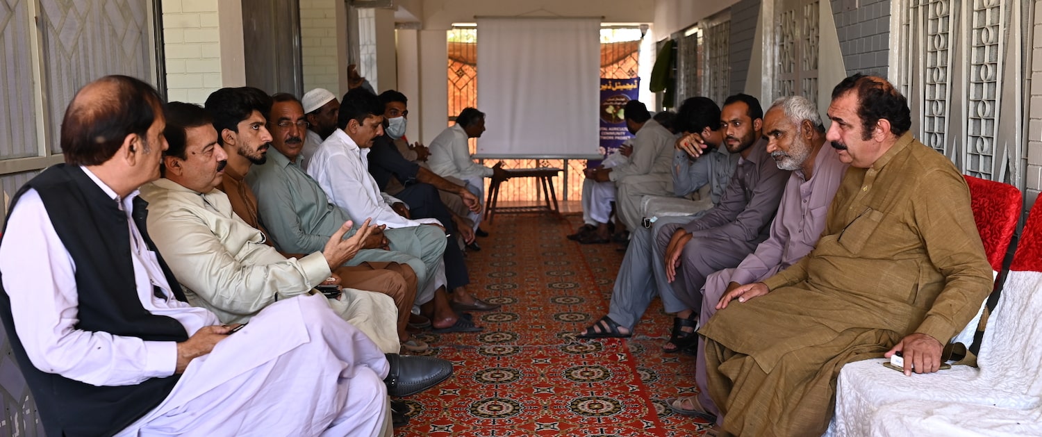 Pakistani men sitting on two benches across each other