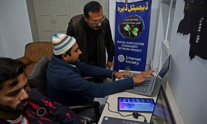 a man pointing to something on computer screen to another man standing next to him