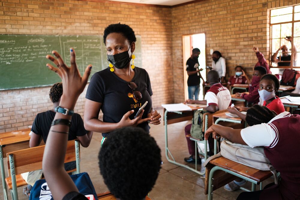 A teacher in the classroom full of kids wearing face mask