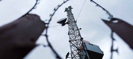 une antenne vue d'en bas derrière du fil barbelé