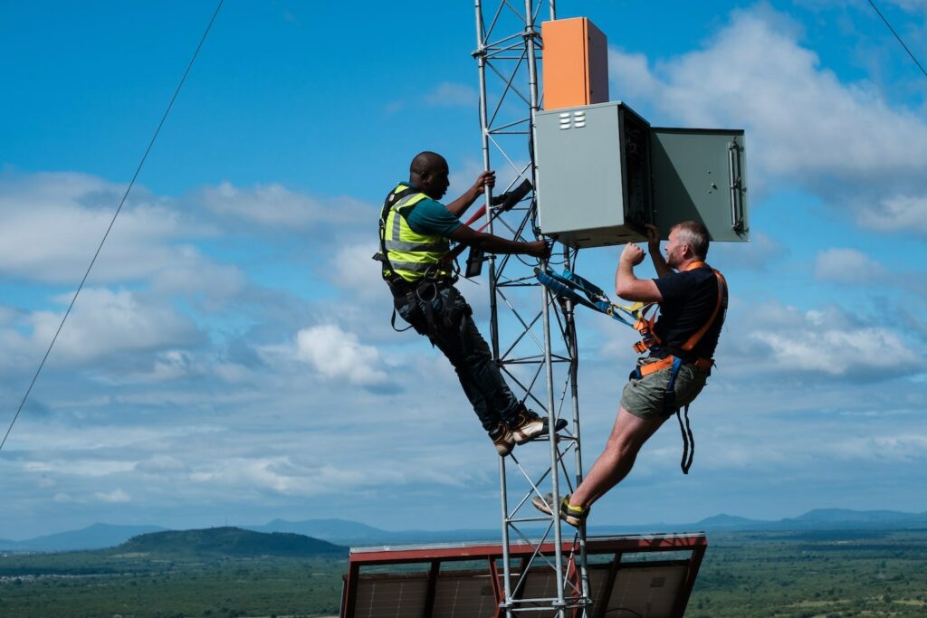 two men climbing on an antenna