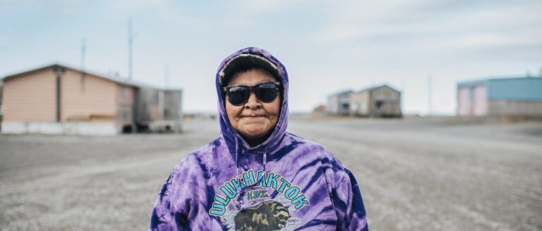 an indigenous woman wearing sunglasses looking at camera
