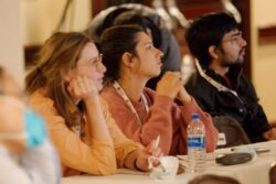 Photo of three participants sitting at a table looking off to the right