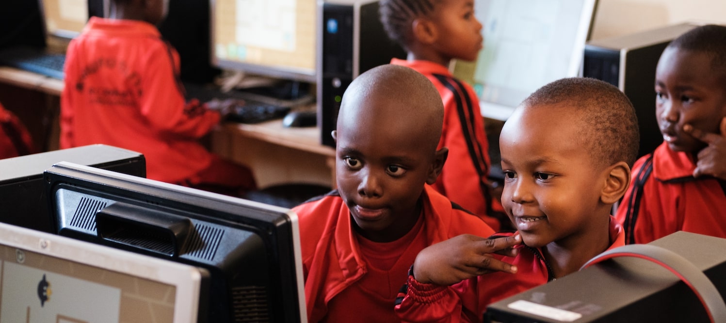 enfants regardant un écran d'ordinateur en souriant