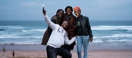 trois femmes debout et un homme tenant un téléphone