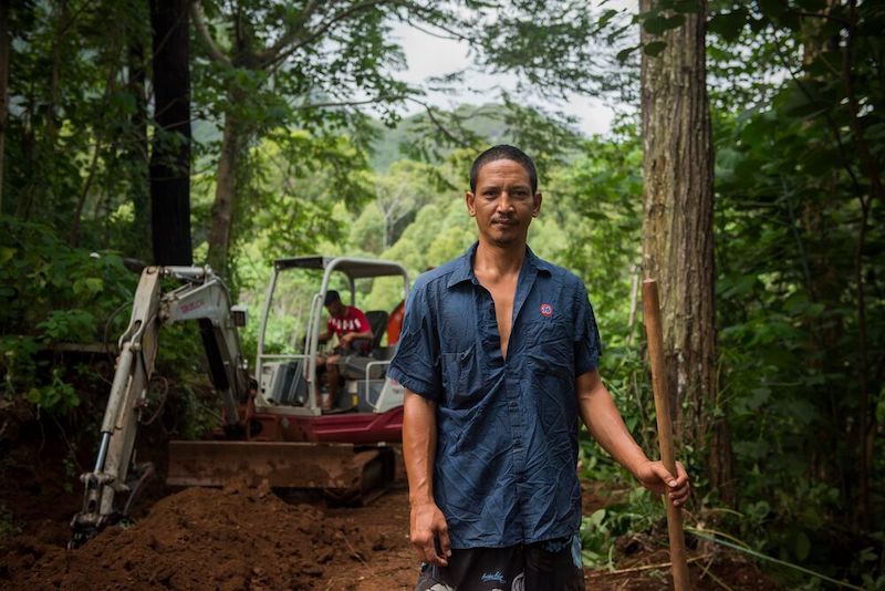 un homme debout sur une route dans les bois
