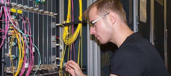 a man with glasses adjusting cables in a patchpanel