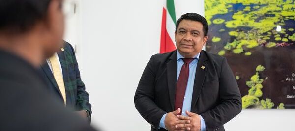 a man in a suit and tie standing in front of two other men