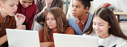 Two Girls Using Laptop with Classmates