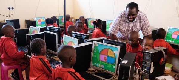niños sentados en un salón de clases frente a las computadoras