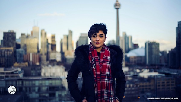 a woman with hands in pockets standing smiling