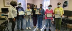 a group of women wearing masks posing for a photo holding plaques