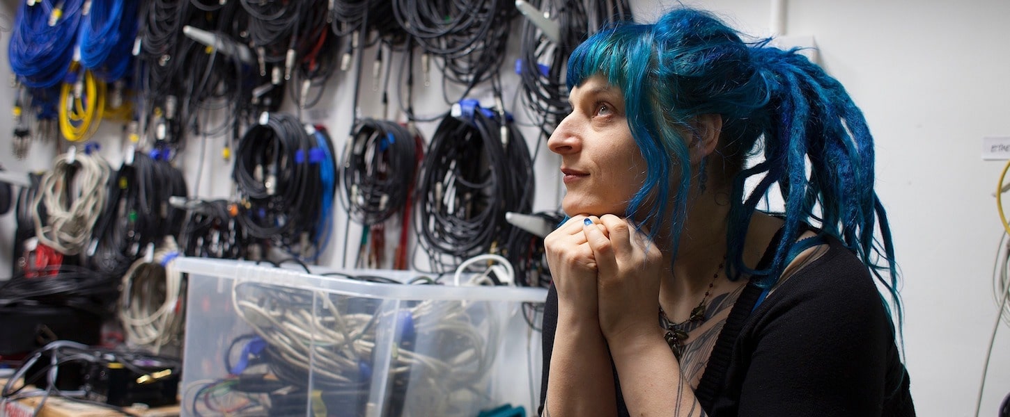 a woman with blue hair looking thoughtfully