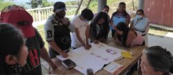 a group of people around the table looking at a white board