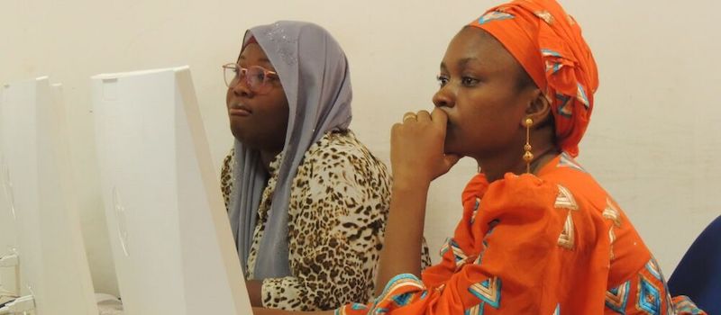 two women siting in front of computer listening to the lesson