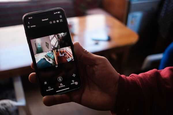 A hand holding a phone with CCTV images on the screen