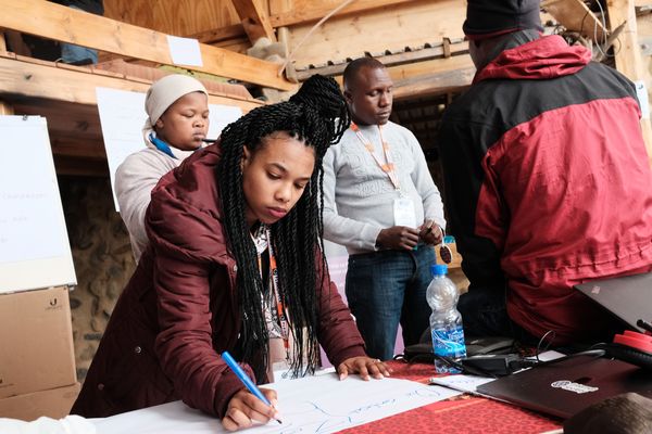 A woman writes on a large piece of paper during the Africa CN summit