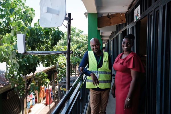 A woman and a man stand by an antenna in Kenya