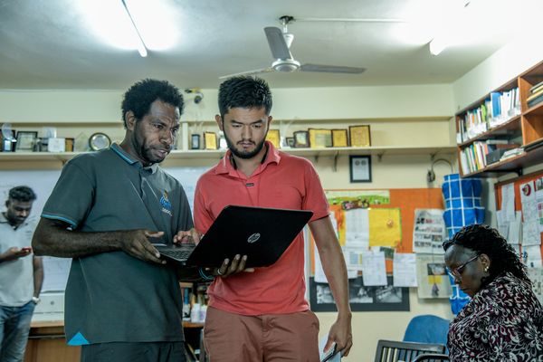 Two men standing and looking at the laptop