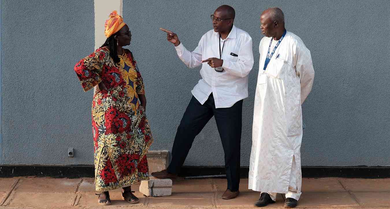 Two men and a woman standing and talking