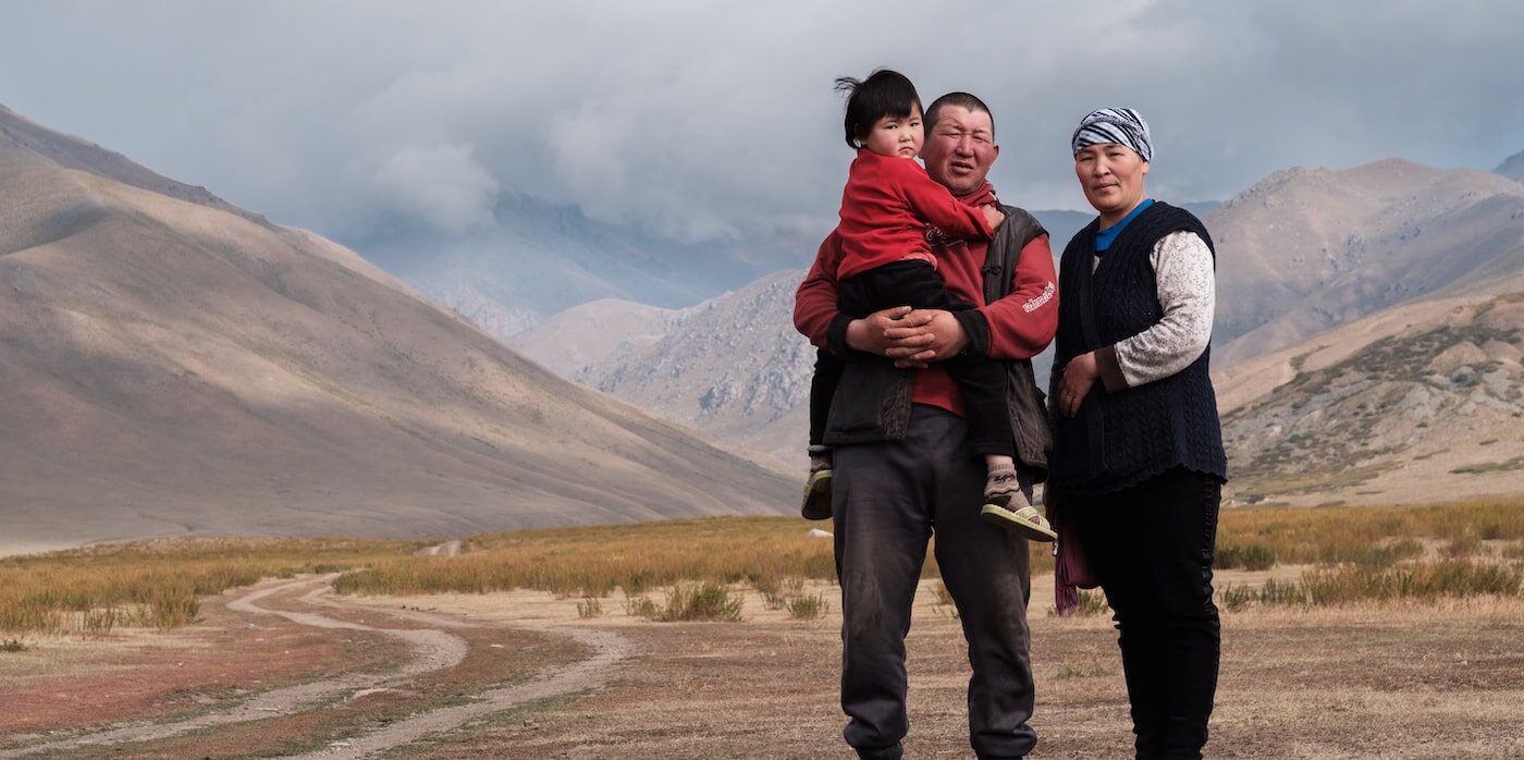 une femme et un homme tenant un enfant posent pour une photo en plein air