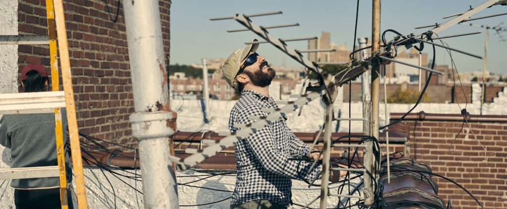 a man on roof installing antenna looking at sky