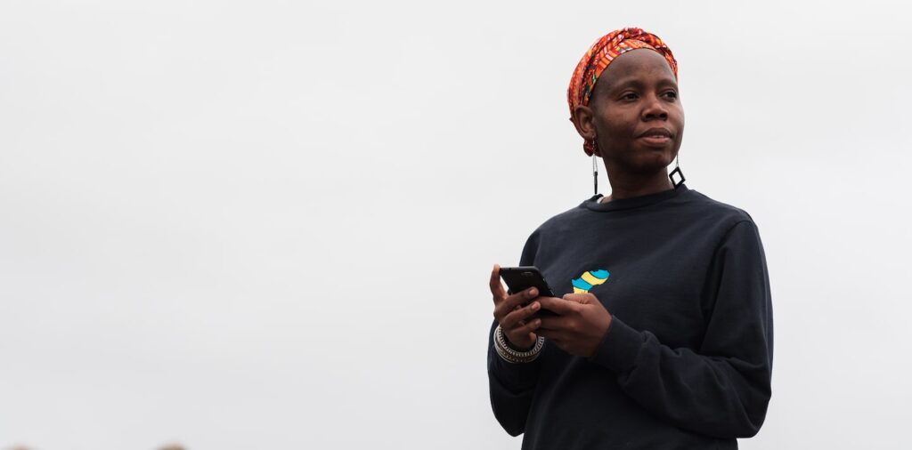 a woman with colorful scarf around head holding mobile